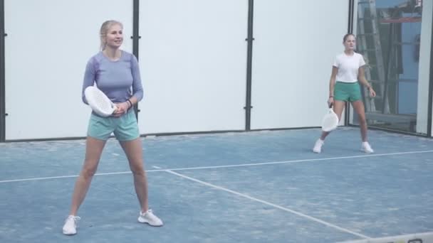 Спортивна жінка грає на велюрі разом з партнером. Перегляд через тенісну мережу — стокове відео