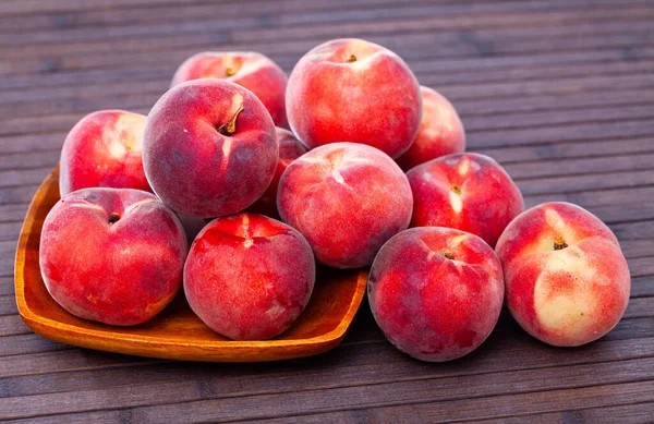 Pêches rouges entières et demi fraîches sur table en bois. — Photo