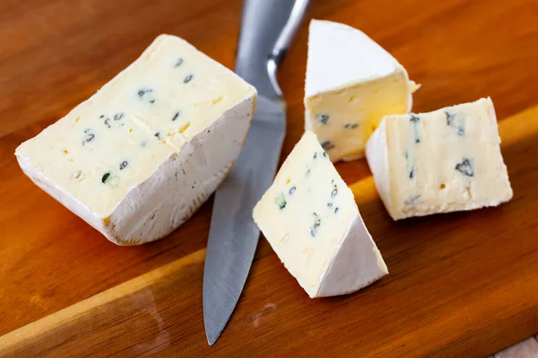 Slices of blue cheese on wooden cutting board — ストック写真