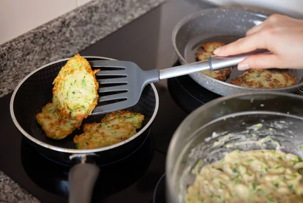 Process frying zucchini pancakes in frying pan in kitchen — Stock Photo, Image