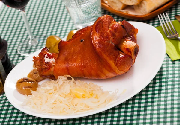 Nudillo de cerdo al horno con patatas y repollo en el plato —  Fotos de Stock