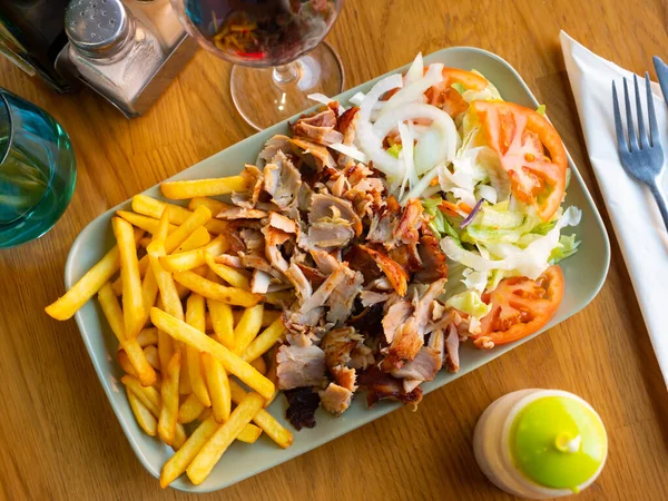 Dish Doner kebab with French fries and a light vegetable salad
