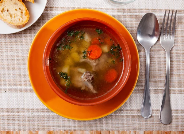 Sopa en caldo de cerdo con patatas, zanahorias, cebollas y hierbas — Foto de Stock