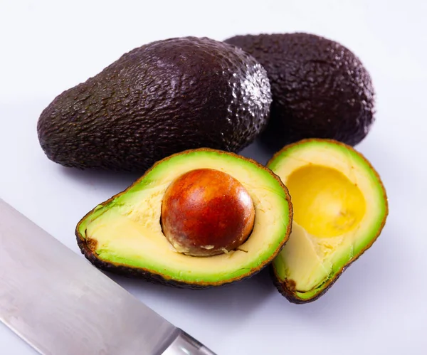 Whole and cut in half Hass avocados on white — Stockfoto