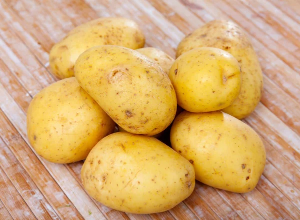 Closeup of fresh organic yellow potatoes on wooden table — Fotografia de Stock