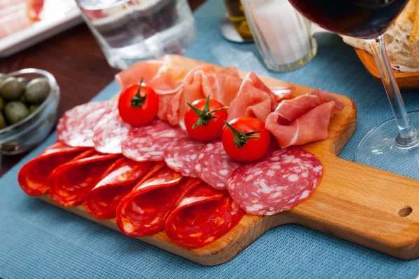 Tapas españolas: rebanadas de salchichas y jamón servidos sobre tabla de madera —  Fotos de Stock