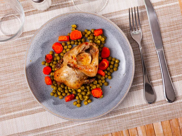 Quaglia al forno servita su piatto con fette di carota e piselli verdi — Foto Stock