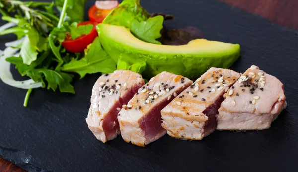Delicious raw tuna fish served with fresh avocado and greens — Stock Photo, Image
