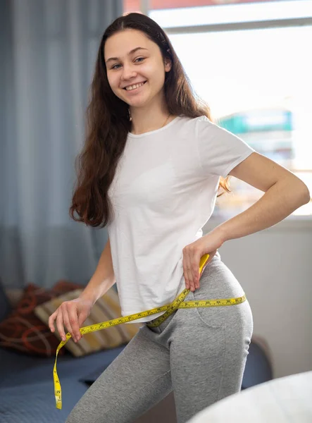 Positive housewife measures waist before eating vegetable salad — Stock Photo, Image