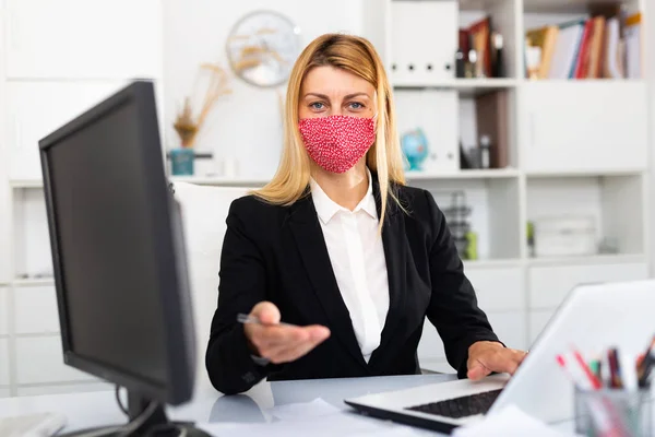 Affärskvinna i färgad medicinsk mask arbetar med bärbar dator — Stockfoto