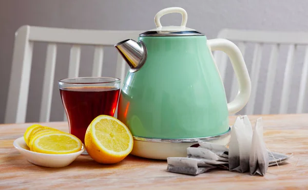 Bollitore elettrico turchese, tazza di tè e limone affettato — Foto Stock