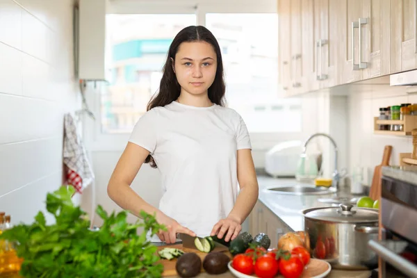 Νεαρή γυναίκα που κόβει λαχανικά στην κουζίνα του σπιτιού — Φωτογραφία Αρχείου