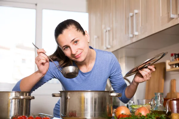 Jeune femme cuisine soupe dans la cuisine — Photo