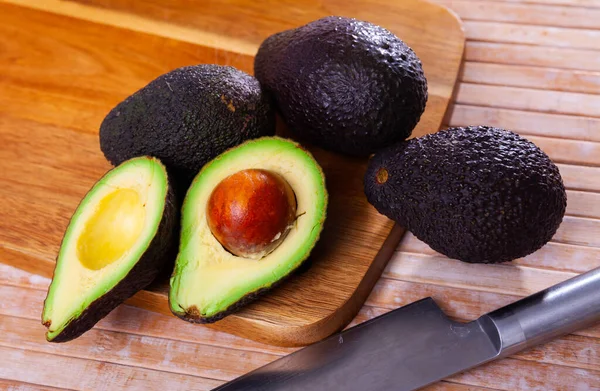 Hele en gehalveerde verse avocado 's op houten ondergrond — Stockfoto