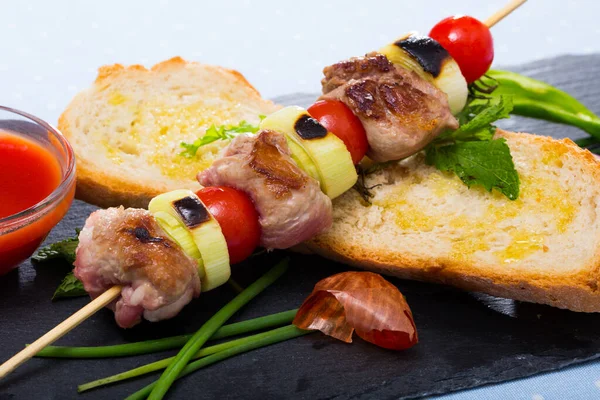 Baked shashlik of lamb with onion and tomatoes served with ketchup and bread — Stock Photo, Image