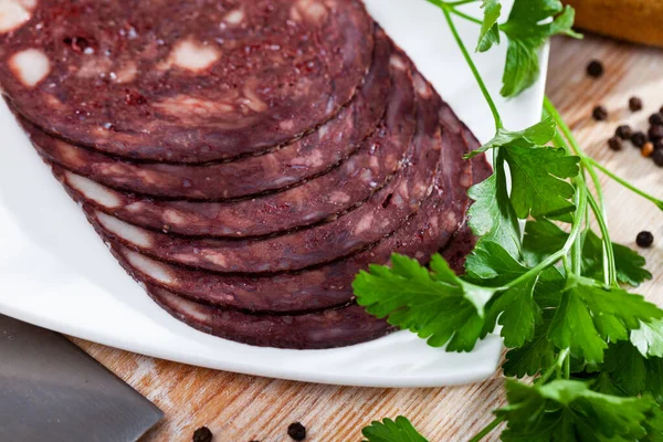 Close-up van Spaanse gerookte bloedworst op witte plaat op houten tafel — Stockfoto