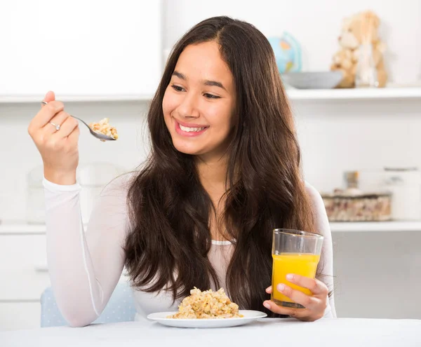 Усміхнена дівчина їсть зернові та п'є сік — стокове фото