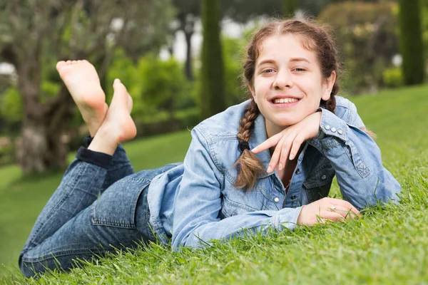 Portret van lachend jong meisje terwijl liggend in de buitenlucht — Stockfoto