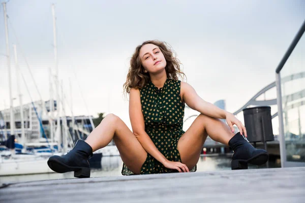 Ung sexig flicka turist i klänning lekfullt poserar vid kajen med båtar — Stockfoto