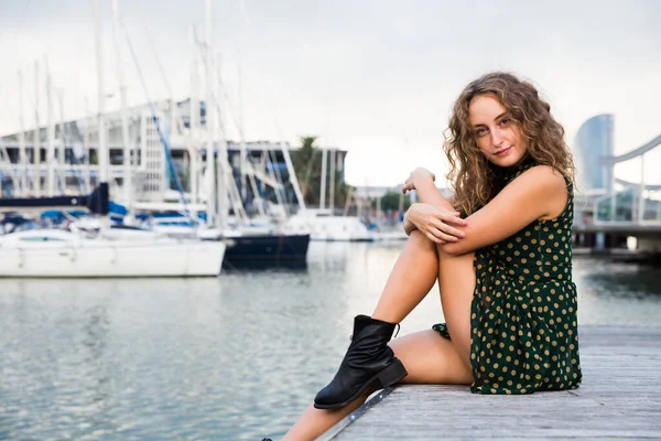 Jovem atraente mulher turista sentado no cais com veleiros no fundo — Fotografia de Stock