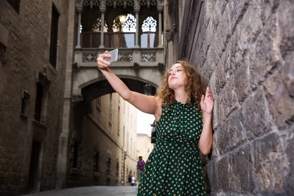 Jovem alegre de pé perto da parede de tijolo e fazer selfie com telefone — Fotografia de Stock