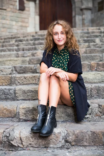 Mladá žena turista v šatech sedí u kamenného schodiště a hravě pózuje — Stock fotografie