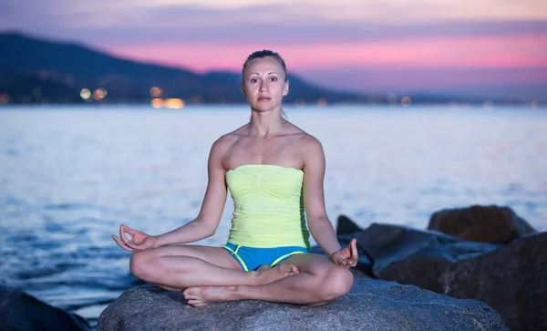 Sportwoman mediteren in yoga padmasana in de avond — Stockfoto