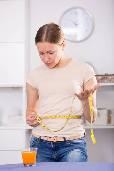 Frustrerad kvinna som mäter midja — Stockfoto