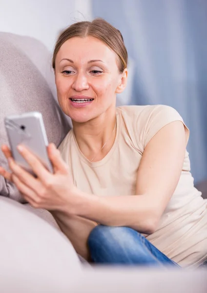 Donna con telefono sul divano — Foto Stock