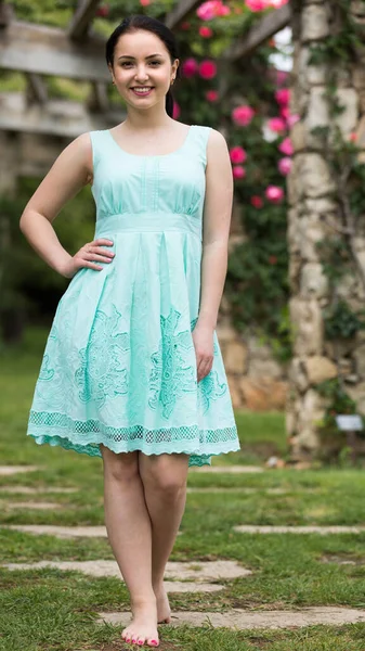 Portret van jonge vrouw in jurk in de buurt van rozen in een tuin — Stockfoto