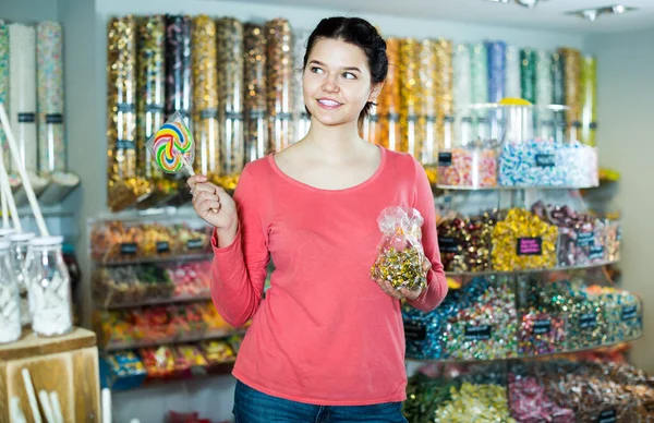 Young woman candies at shop display
