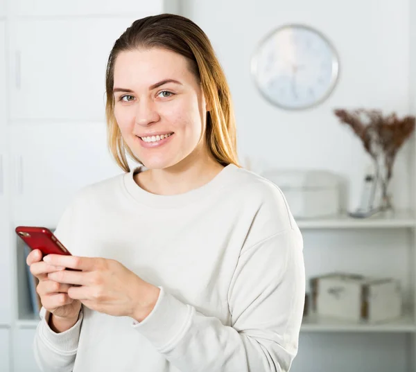 Ung Kvinne Hviler Smiler Med Telefonen Hjemme – stockfoto