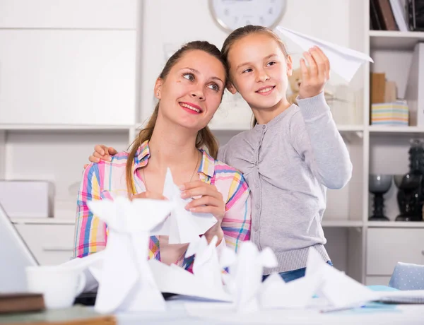 若い笑顔の女性と女の子は自宅で紙の飛行機を作る — ストック写真