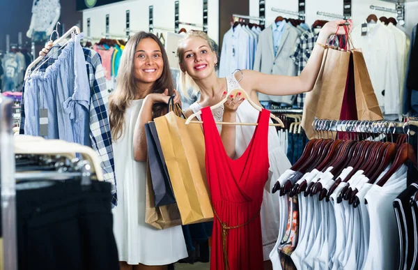 Två Glada Leende Flickor Som Håller Klädställningar Och Shoppingväskor Stående — Stockfoto