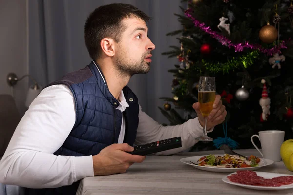 男持っているクリスマスディナーとともにシャンパンとテレビを見ますホーム — ストック写真