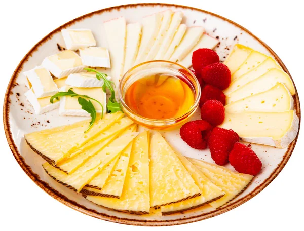 さまざまな種類のチーズがスライスされ 蜂蜜とラズベリーの小さなボウルとプレート上で提供されます 白地に隔離された — ストック写真