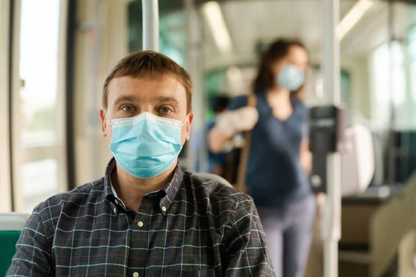 Man in protective medical mask and gloves rides in public transport