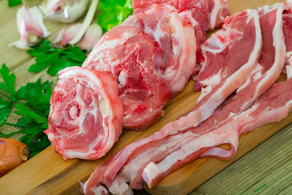 新鮮な野菜や緑を背景に木製のまな板上の生ラム肉肉 — ストック写真