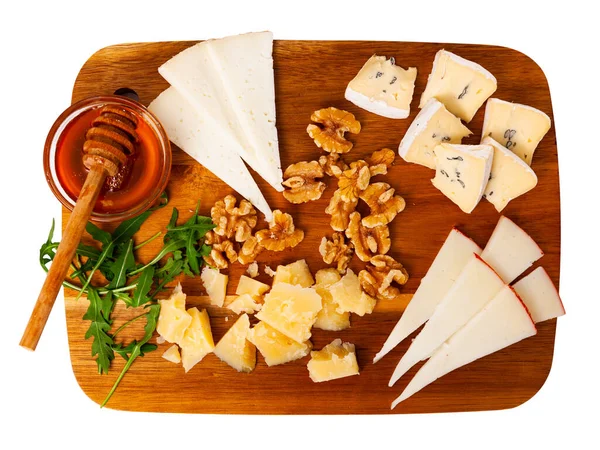 Cheese board with different types of delicious cheese on wooden cutting board. Isolated on white background