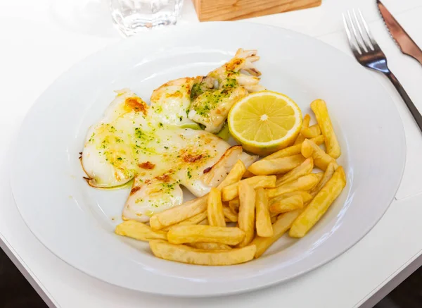 Image of delicious grilled cuttlefish on plate, served with french fries