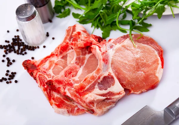 Fresh raw pork loin chops on white background with condiments