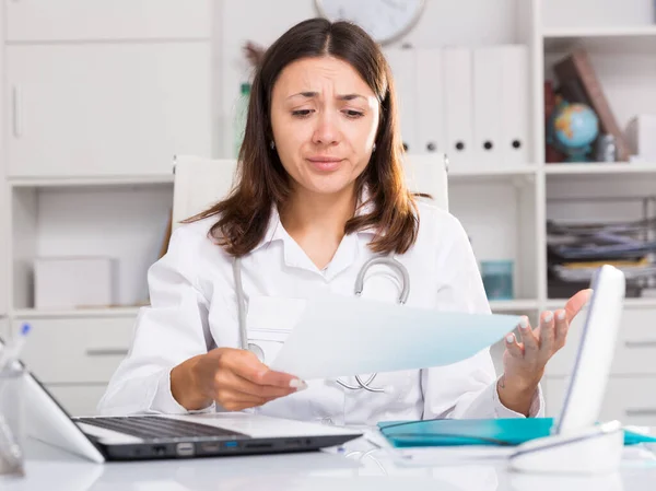 Aufgebrachte Ärztin Uniform Mit Papieren Hinter Laptop Krankenhaus — Stockfoto