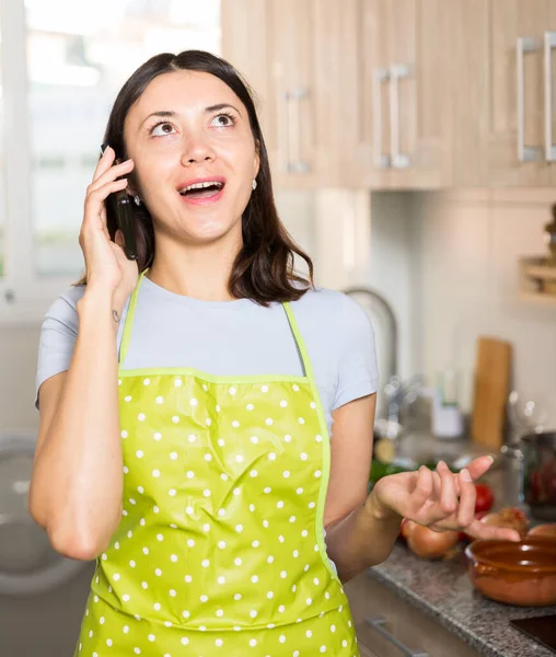 Θετική Γυναίκα Νοικοκυρά Ποδιά Μιλάει Στο Τηλέφωνο Στο Σπίτι Κουζίνα — Φωτογραφία Αρχείου
