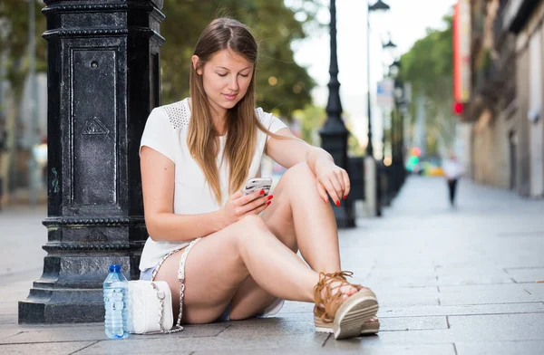 Chica Soñadora Usando Teléfono Mientras Relaja Cerca Del Poste Lámpara —  Fotos de Stock