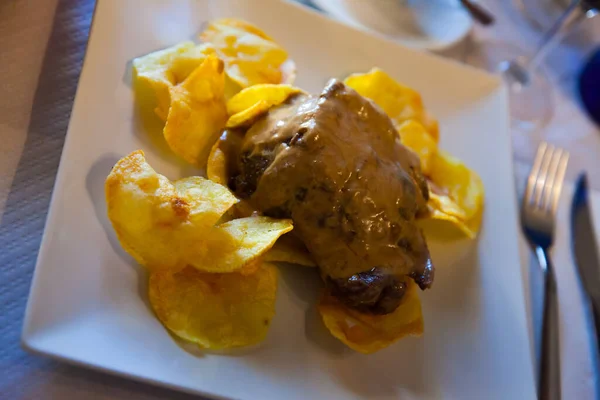 Delicious meat dish - pork cheeks in red wine served with potato chips
