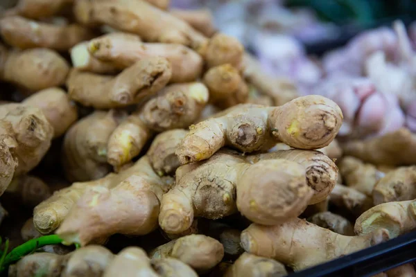 Fresh ginger root on showcase of greengrocery shop for sale to customers. High quality photo