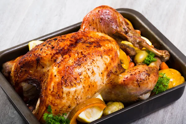 Delicious roasted turkey garnished with baked apples, vegetables and greens..