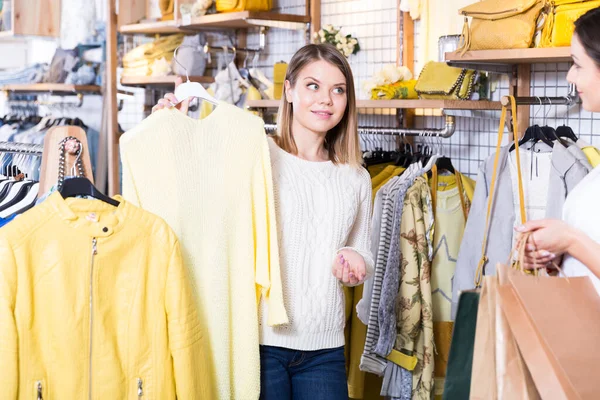 若いです女性アシスタントデモンストレーションファッション黄色Pulloverへ女性でブティック — ストック写真