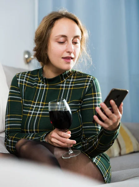Young Woman Using Smartphone While Sitting Glass Wine Sofa — Zdjęcie stockowe