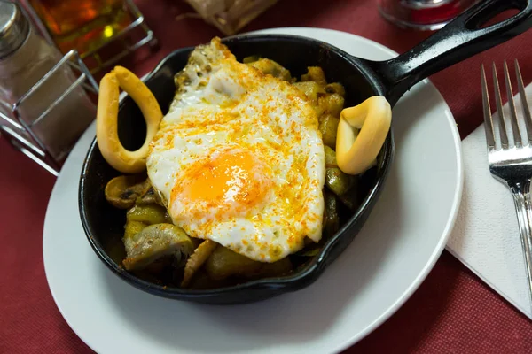 Nutritious snack in frying pan - champignons, scrambled eggs and Galician potato